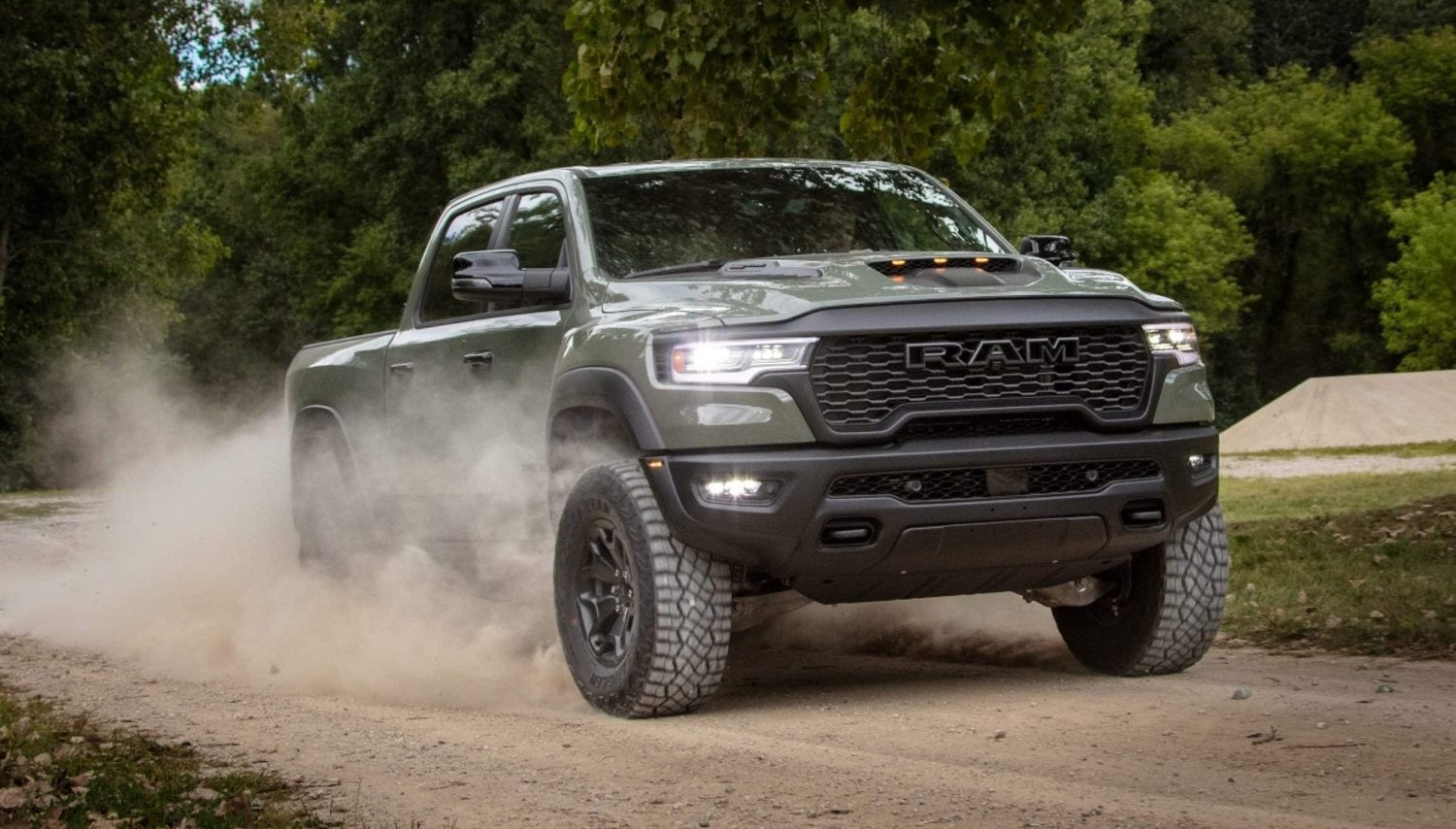 Green 2026 Ram 1500 RHO 4x4 crew cab kicking up dust on a dirt road