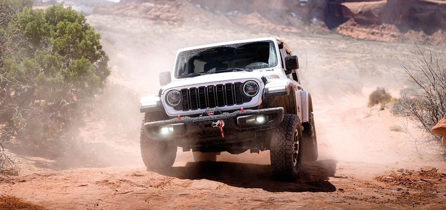 White 2026 Jeep Wrangler Rubicon X on a sandy off road trail in the desert