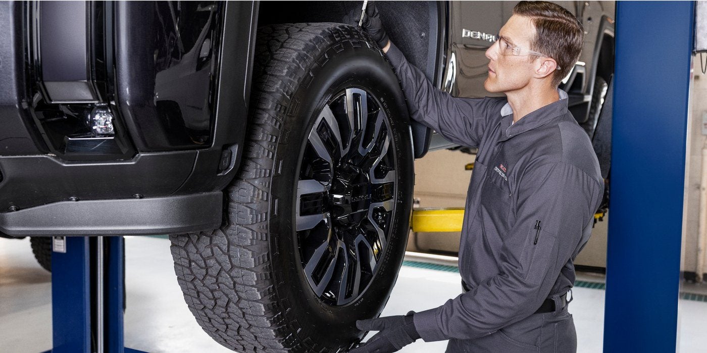 Technician working on a vehicle raised on a lift in the Holiday CDJR service shop in Graham