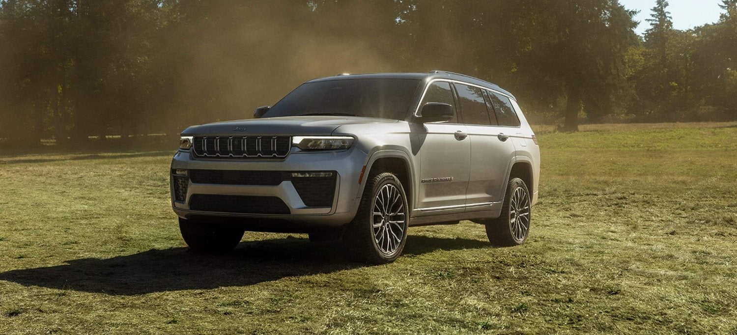 Silver 2026 Jeep Grand Cherokee Summit parked in a grassy field