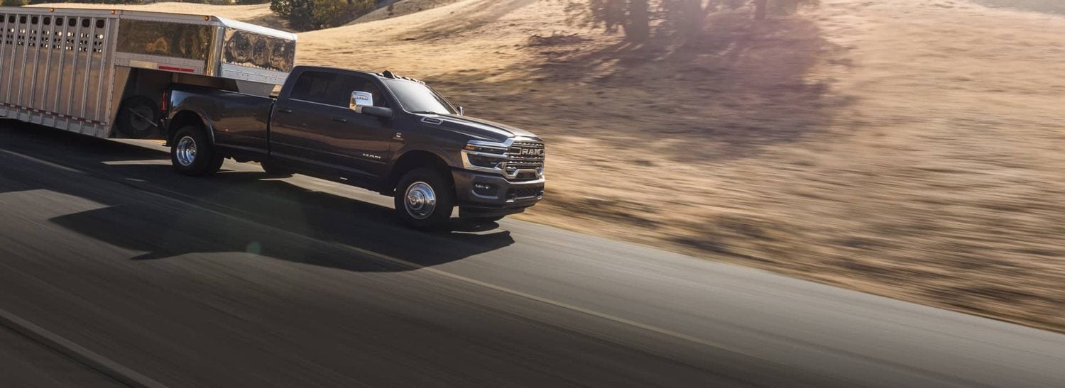Gray 2026 Ram 3500 Limited Longhorn crew cab towing a large trailer