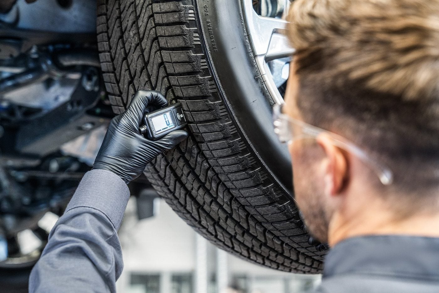 Technician checking tireTechnician checking tire tread depth in Graham, Texas tread depth in Graham, Texas